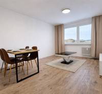 Dining table and coffee table on a floor with a wood decor in a 2-room apartment.