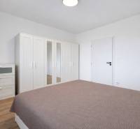 Bedroom with a white wardrobe and dresser in a 2-room apartment, floor with wooden decor.