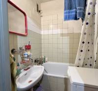A bathroom in a 3-room apartment with a bathtub, sink, and washing machine.