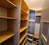 Storage space with shelves in a two-room apartment with a wood-patterned floor.