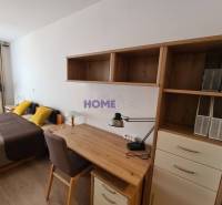 A desk with shelves, a bed, and a floor with a wooden decor in a 2-room apartment.