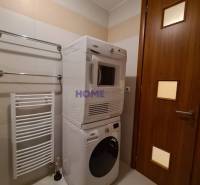 Bathroom in a 2-room apartment with a washing machine and dryer, white radiator on the wall.
