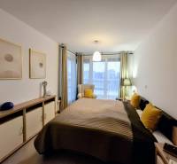 Bedroom with a bed, decorative pillows, and a dresser in a two-room apartment.