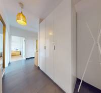 A hallway in a 3-room apartment with built-in wardrobes and a mirror, flooring with a wooden decor.