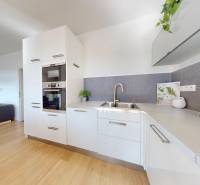 A kitchen in a 3-room apartment with a wooden decor floor, white cabinets, and appliances.