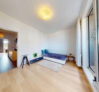 A room in a three-room apartment with a wooden decor floor and glass doors to the balcony.