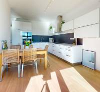 A bright kitchen in a 3-room apartment with a wooden decor floor and a dining table.