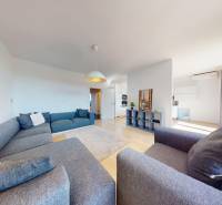 Living room of a three-room apartment with a large sofa and a floor with a wooden decor.