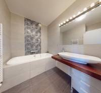 Bathroom in a 3-room apartment with a bathtub, mirror, and patterned tiles above the bathtub.