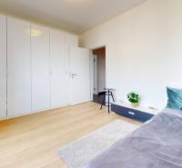 A bright bedroom with wood-patterned flooring and a built-in wardrobe in a 3-room apartment.