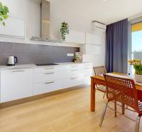 A kitchen in a 3-room apartment with a wooden decor floor and a dining table.