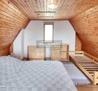 Attic room with a wooden-clad roof and walls, a bed, and a dresser.