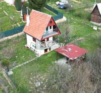 A family house and gardens in Čachtice with a pergola and surrounding vegetation.