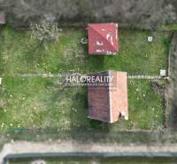 Gardens in Čachtice with a lawn and two roofs, aerial view.