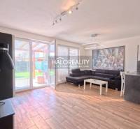 2-room apartment with wood-patterned flooring, a sofa, and a kitchenette.
