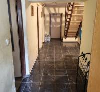 Interior of a family house with dark tiles and a wooden staircase.
