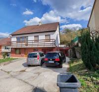 A family house on Závršky Street in Myjava, a parking lot with two cars and greenery.