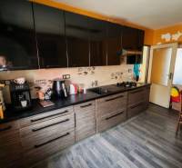 A kitchen with black cabinets and a wood-decorated floor in a family house.