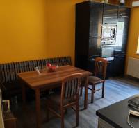 Dining room in a family house with a wooden table, chairs, and a floor with a wooden decor.