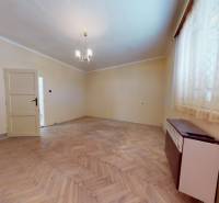 A room in a family house with a floor featuring a wooden decor and a simple chandelier.
