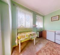 A kitchen in a family house with retro appliances and a table by green walls.