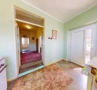 A hallway with carpets and a table in a family house, green walls, large glass doors.
