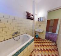 A bathroom in a family house with tiles and a bathtub.
