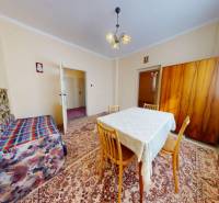 Living room in a family house with a carpet, table, sofa, and cabinet.