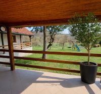 Terrace in a family house in Podbranč, overlooking a garden with a swing and a slide.