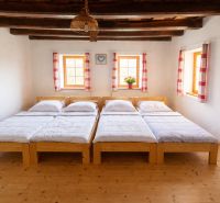 Wooden beds and ceiling beams in a family house with a floor featuring a wood decor.