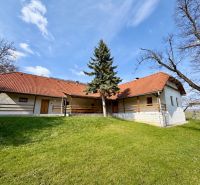 A family house in Podbranč with a red roof surrounded by greenery and trees.