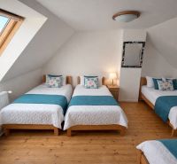 Attic bedroom with four beds and a wooden decor floor in a family house.