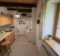 A kitchen with tiles in a family house with wooden beams and a fully equipped kitchenette.