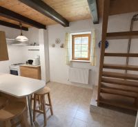 A kitchen in a family house with wooden decor, open stairs, and tables.