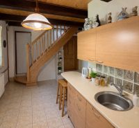 A family house with a kitchen, staircase, bar stools, and a wooden-patterned floor.