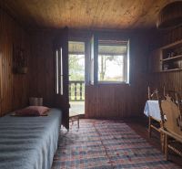 Interior of a cabin with wooden decor, bed, table, chairs, and a small rug.
