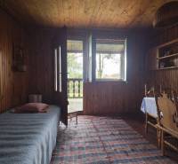 Interior of a cabin with wooden decor, bed, table, chairs, and a small rug.
