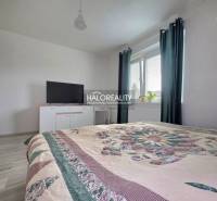 A bedroom in a family house with a bed, a television, and a window with dark curtains.