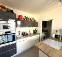 A kitchen in a 3-room apartment with a wooden decor floor, built-in appliances, and decorations.