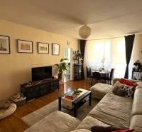 Living room of a 3-room apartment with a sofa, television, and dining table, floor with wooden decor.
