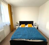 A bedroom with a bed, yellow pillows, and a blue blanket in a 3-room apartment.