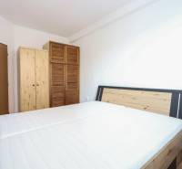 A bedroom in a 2-room apartment with a bed and wooden wardrobes, flooring with a wooden decor.
