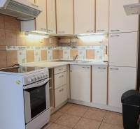 Kitchen in a 2-room apartment with white cabinets and a stove, floor with wood decor.