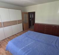 A bedroom in a studio apartment with wood-patterned flooring and practical furniture.