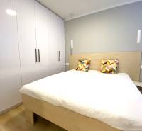 Bedroom with a double bed, colorful pillows, and a wardrobe, 2-room apartment.