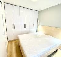 Bedroom with a double bed, white wardrobe, and wooden decor flooring in a two-room apartment.