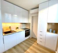 A kitchen in a 2-room apartment with white cabinets and a wood-patterned floor.