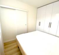 Bedroom in a 2-room apartment with a bed and a large built-in wardrobe.