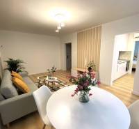 Dining room in a 2-room apartment with a white table and a wooden decor floor.