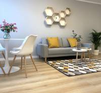 Living room of a two-room apartment with a wooden decor floor, gray sofa, and decorative hexagons.